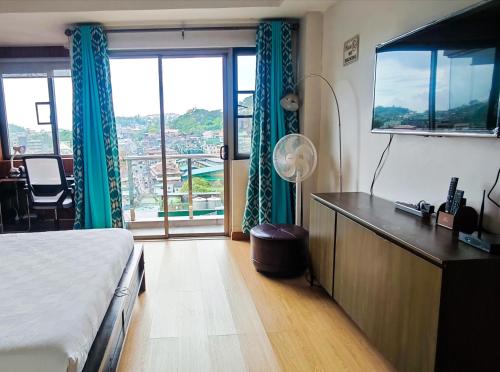 ein Hotelzimmer mit einem Bett und einem großen Fenster in der Unterkunft Baguio Cedar Peak Balcony with View Near Session Road in Baguio City
