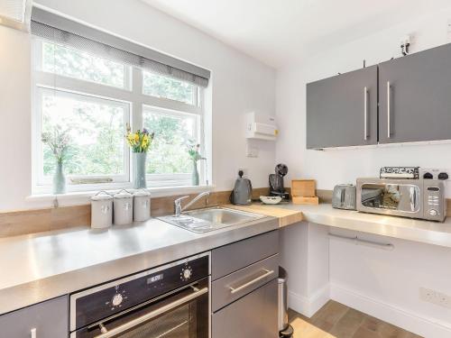 a kitchen with a sink and a microwave at Peacock On The Pin in Stisted