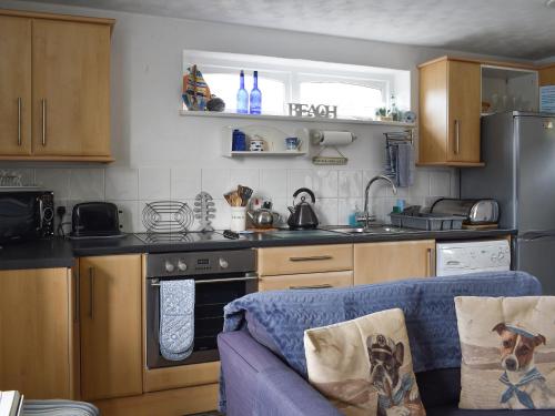 a kitchen with a blue couch in front of a stove at Garden Cottage - Uk30590 in Polperro