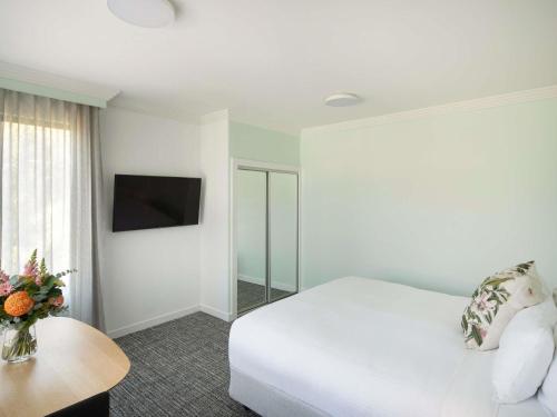 a bedroom with a white bed and a tv at The Sebel Kiama in Kiama