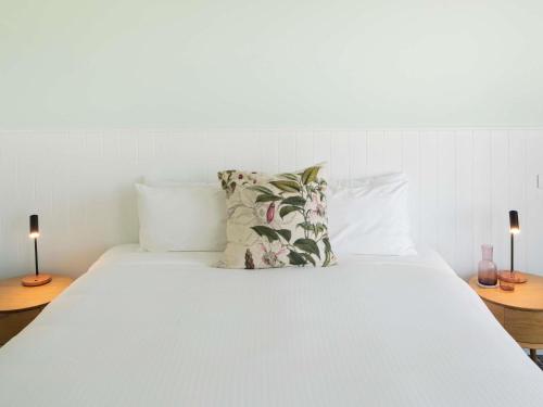a white bed with two lamps on two tables at The Sebel Kiama in Kiama