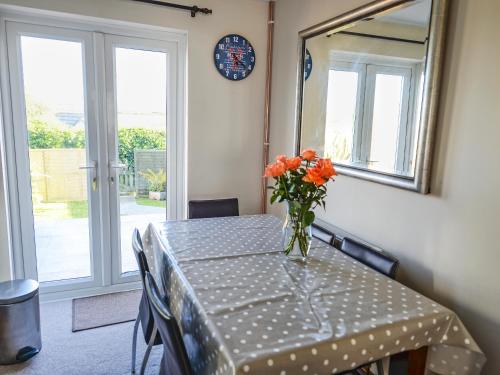 ein Tisch mit einer Vase mit orangefarbenen Blumen darauf in der Unterkunft The Yellow House in Padstow