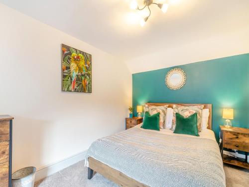 a bedroom with a large bed with green walls at Raven Cottage in Barnard Castle