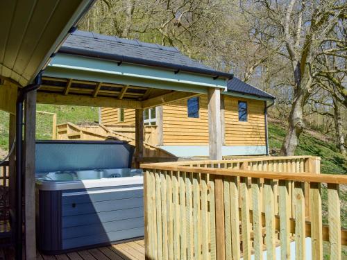 a hot tub on a deck next to a cabin at Red Kite Lodge - Uk32610 in Old Radnor