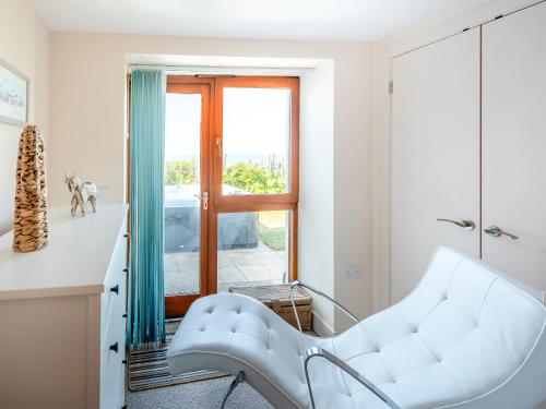 Una silla blanca en una habitación con ventana en Beachbreak - Uk42996, en Woolacombe