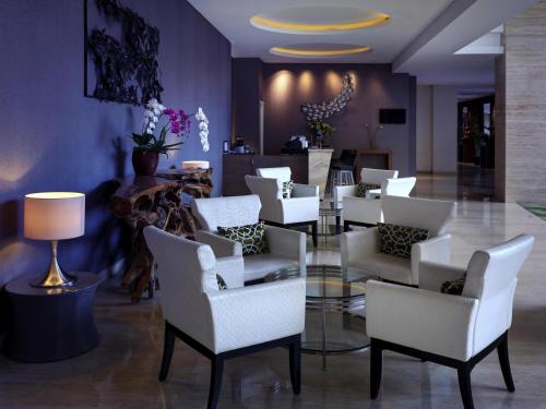 a lobby with white chairs and a glass table at Grand Mercure Bandung Setiabudi in Bandung