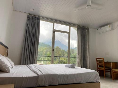 a bedroom with a bed and a large window at 300 Hills Fort in Meppādi