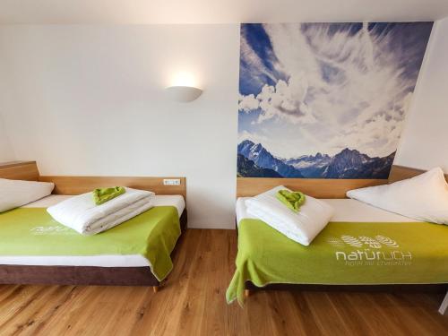 two beds in a room with a painting on the wall at Natürlich Hotel mit Charakter in Fiss