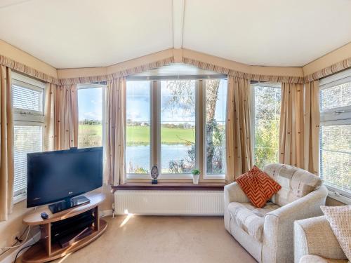 a living room with a tv and a large window at Hafod Caravan - Uk45717 in Brynteg