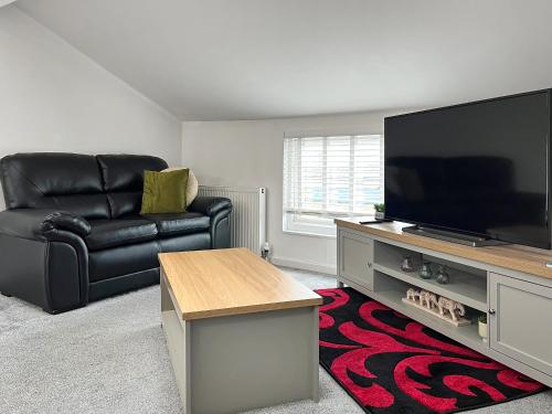 a living room with a black leather chair and a flat screen tv at Regent House in Scarborough