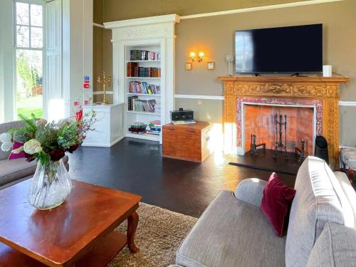 a living room with a fireplace with a tv above it at The Mansion House At Kirkhill in Arniston