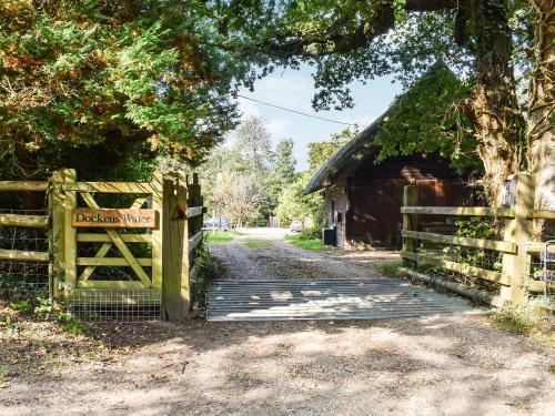 a wooden gate with a sign on it next to a barn at The Cottage At Dockens Water in Fritham