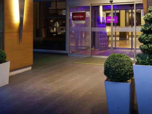 an entrance to a building with two potted plants at Mercure Paris Velizy in Vélizy-Villacoublay