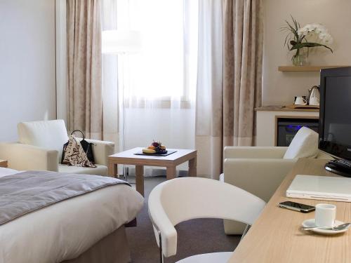a hotel room with a bed and a table and chairs at Mercure Paris Velizy in Vélizy-Villacoublay