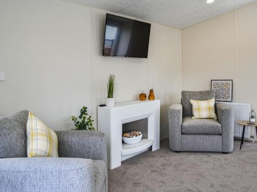 a living room with two chairs and a tv on the wall at Lodge 43 Bridlington Holiday Park - Uk47517 in Carnaby
