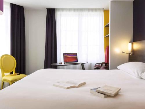 a bedroom with a bed with a book and a laptop at ibis Styles Saumur Gare Centre in Saumur