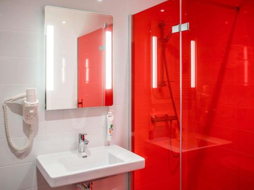 a red bathroom with a sink and a shower at ibis Styles Saumur Gare Centre in Saumur