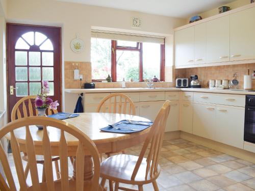 a kitchen with a wooden table and chairs and a table and a window at The Byre in Pencombe