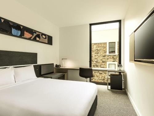 a hotel room with a bed and a television at ibis Adelaide in Adelaide