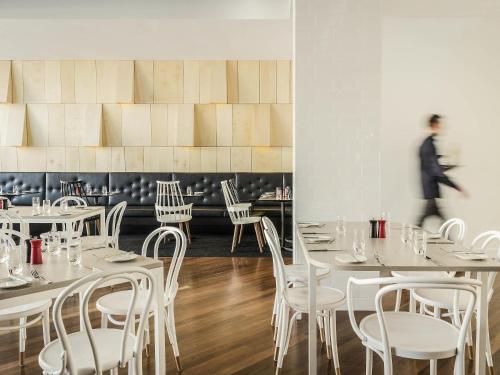 a dining room with white tables and white chairs at ibis Adelaide in Adelaide