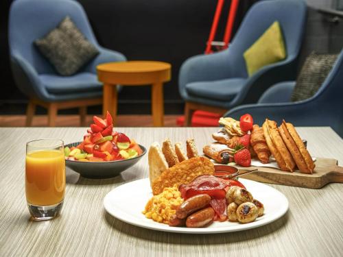 a table with a plate of breakfast food and a glass of orange juice at ibis Adelaide in Adelaide