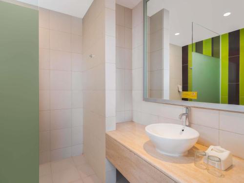 une salle de bain avec un lavabo et un miroir dans l'établissement Ibis Styles Malang, à Malang