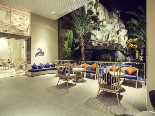 a lobby with chairs and a wall with a dinosaur at Mercure Pattaya Ocean Resort in Pattaya Central