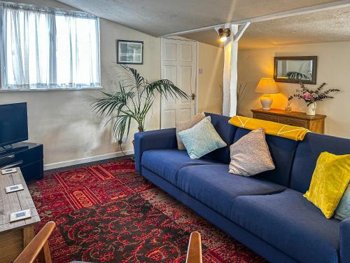 a living room with a blue couch and a tv at Osokozy Cottage in Shrawley