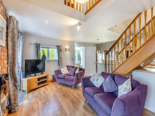 a living room with two purple couches and a tv at Ty Teiliwr - Uk45719 in Brynteg
