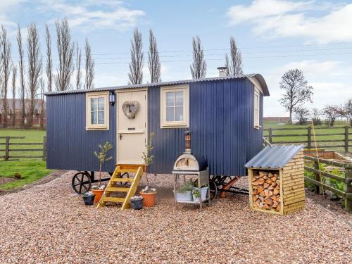 a tiny house with a blue roof and a grill at The Lambing Shed in Ryhill