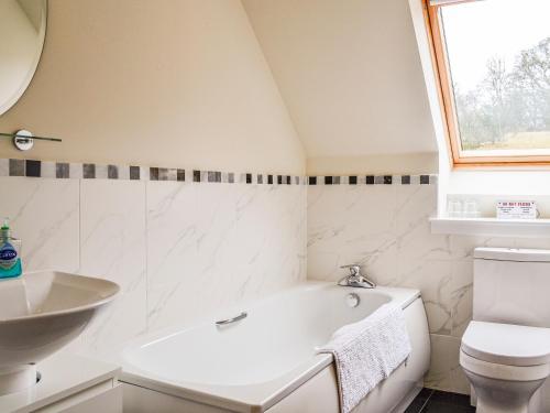 a bathroom with a white tub and a sink at Woodside in Blairgowrie