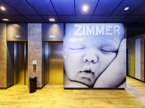 a large sign in a hallway with a baby on it at ibis budget Ludwigsburg in Ludwigsburg