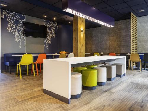a waiting area with yellow and blue tables and chairs at ibis budget Ludwigsburg in Ludwigsburg