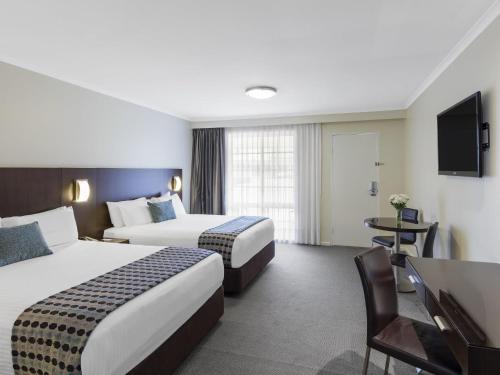 a hotel room with two beds and a table at Mercure Wagga Wagga in Wagga Wagga