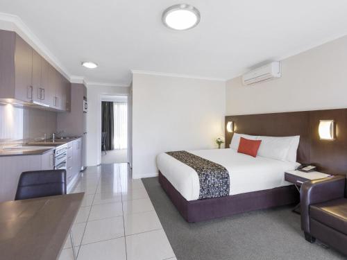 a hotel room with a bed and a kitchen at Mercure Wagga Wagga in Wagga Wagga