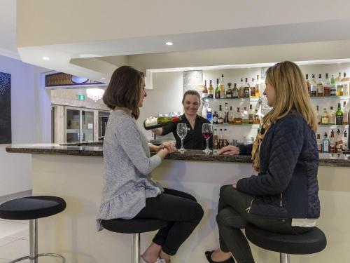 two women sitting at a bar with a bartender at Mercure Wagga Wagga in Wagga Wagga