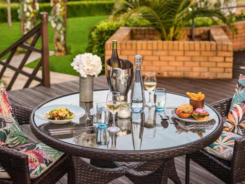 a table with glasses of wine and food on it at Mercure Milton Keynes Hotel in Milton Keynes