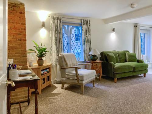 a living room with a green couch and a chair at The Friars Apartment, Eastbridge Hospital in Canterbury