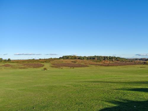 a green field of grass with a hill in the background at The Coach House in Fordingbridge