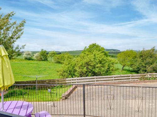 a patio with a fence and two chairs and an umbrella at Laird House in Lochmaben
