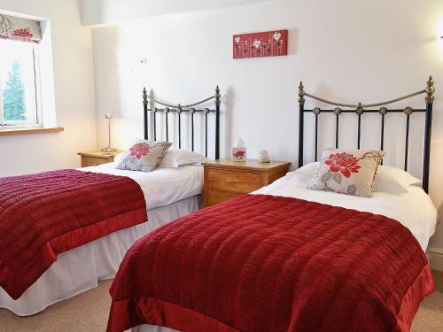 a bedroom with two beds with red and white blankets at Swallows Nest in Soulby