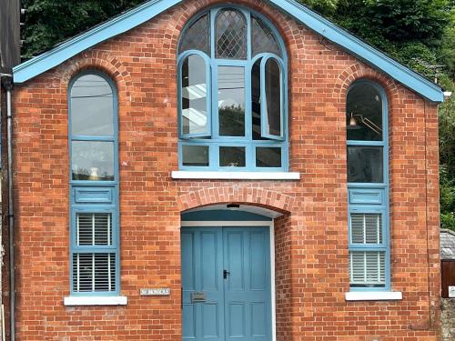 een bakstenen gebouw met een blauwe deur en twee ramen bij St Monicas in Fowey