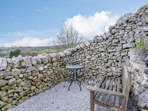 a stone wall with a table and a bench at Limecroft in Malham