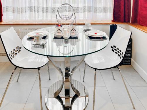 a glass table and two chairs with cups and saucers at Black Pan Holiday Cottage in Shanklin