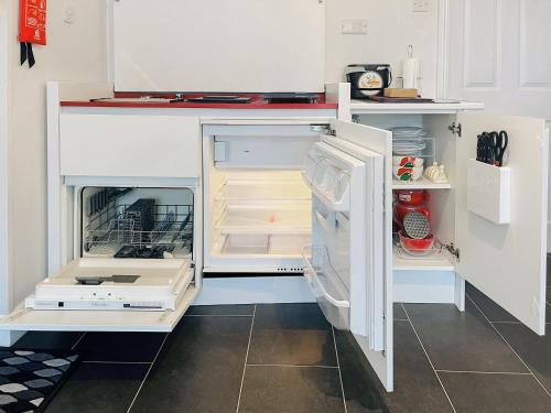 a white refrigerator with its door open in a kitchen at Black Pan Holiday Cottage in Shanklin