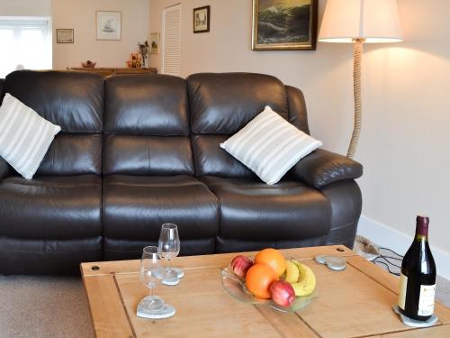 a brown leather couch with a table with fruit and wine glasses at 5 Coast Lodge in Pevensey