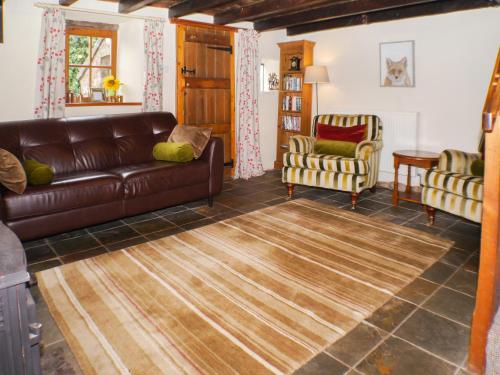 een woonkamer met een leren bank en 2 stoelen bij Garden Cottage in Onecote
