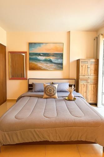a bedroom with a large bed with a painting on the wall at The Opal residence IBR in Sharjah