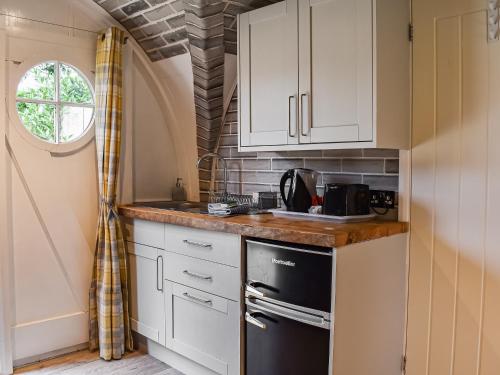 a kitchen with white cabinets and a black refrigerator at The Hobbit House in Hastingleigh