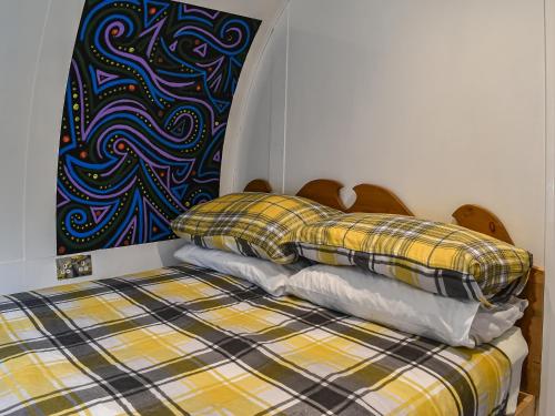 a bed with two pillows and a painting on the wall at The Hobbit House in Hastingleigh